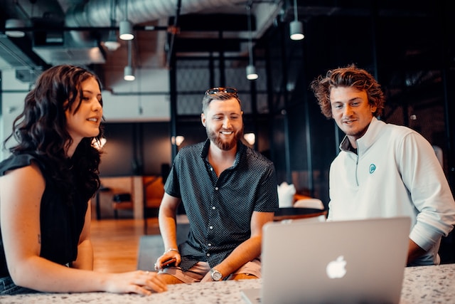 three people collaborating around a laptop together